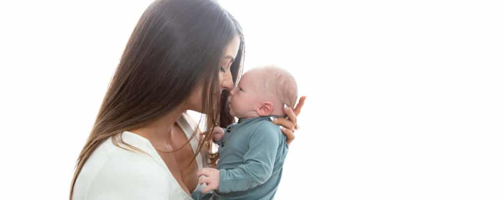 mom kissing newborn baby