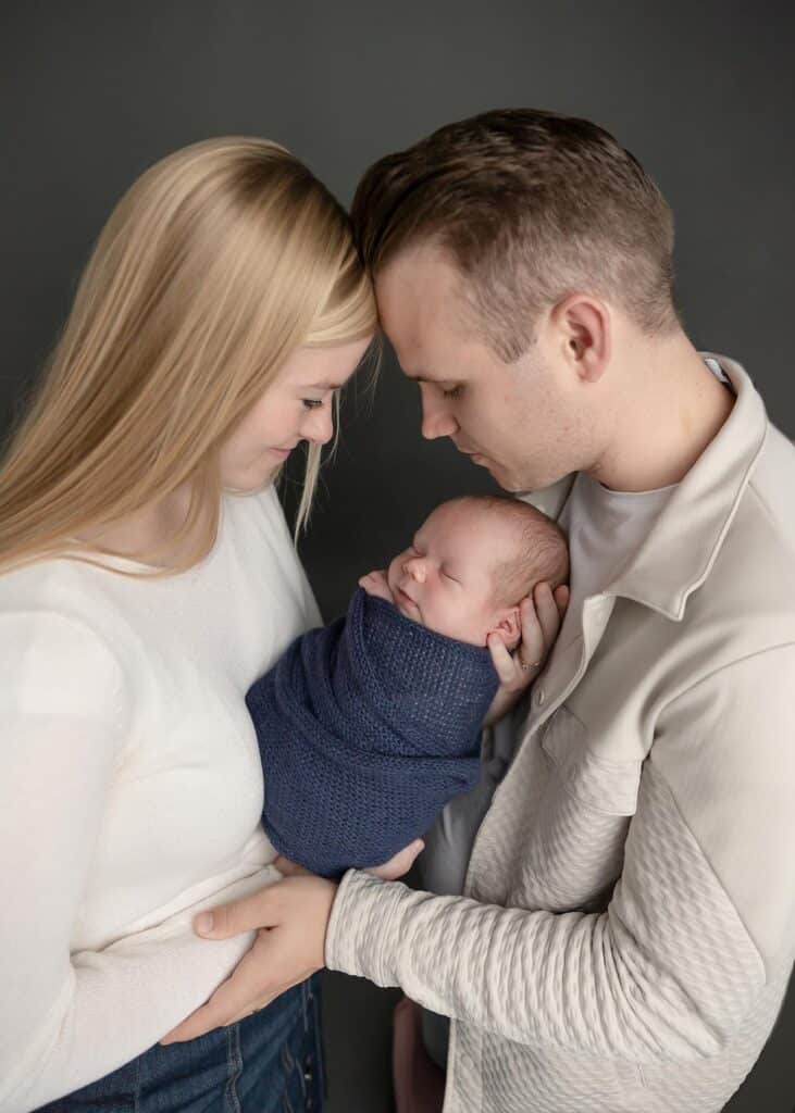 mom and dad with baby boy in blue wrap