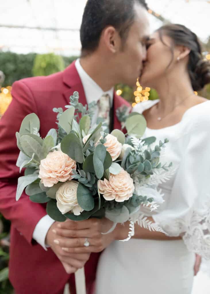 bride and groom holding bouquet and kissing