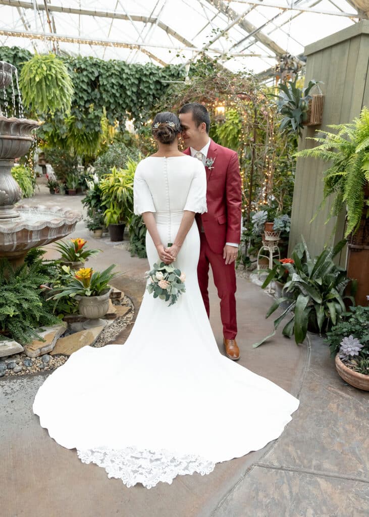 back of brides dress with groom whispering in her ear