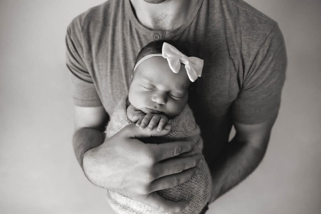 dad holding newborn girl closeup in black and white taken by a provo newborn photographer