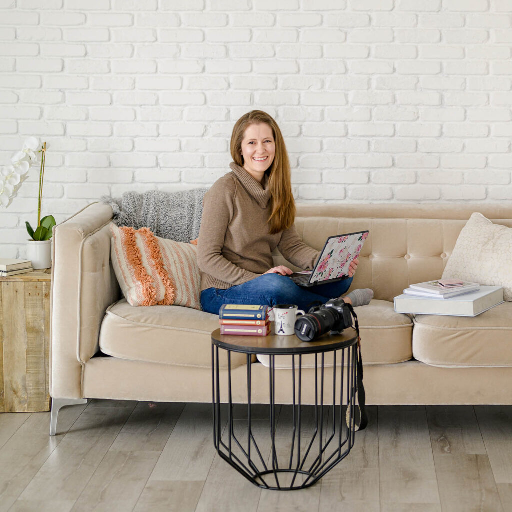 utah county photographer sitting on tan couch editing photos