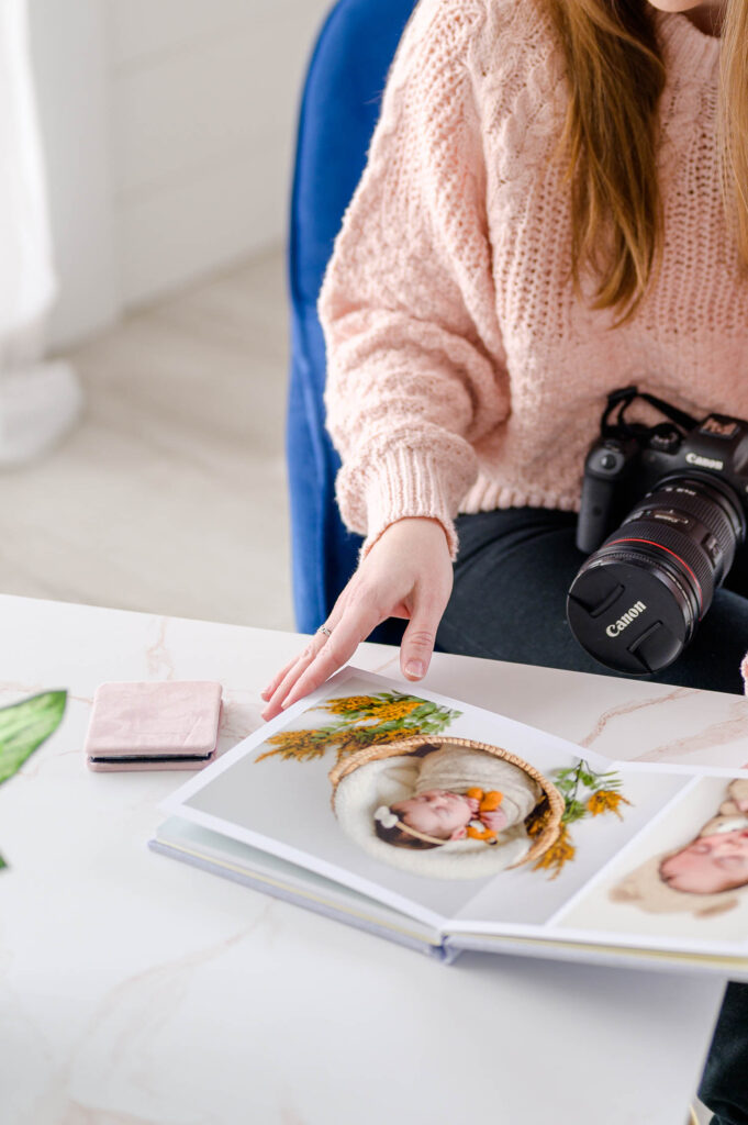 utah county newborn photographer looking through portrait album with newborn portraits