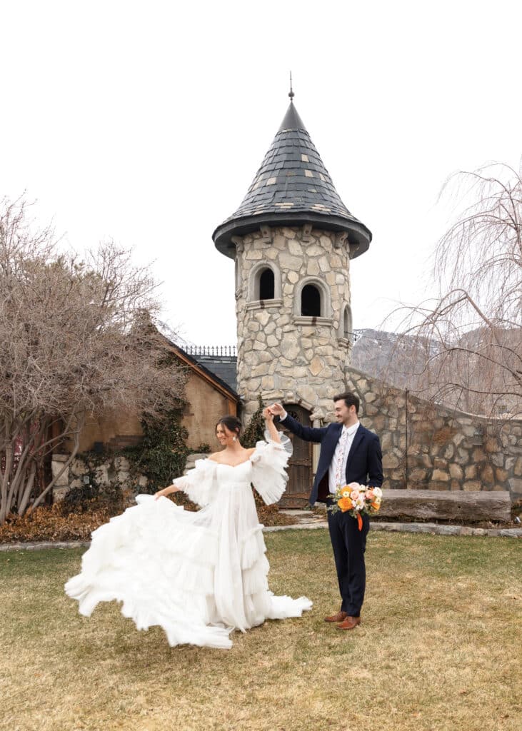 groom twirling bride in front of castle tower