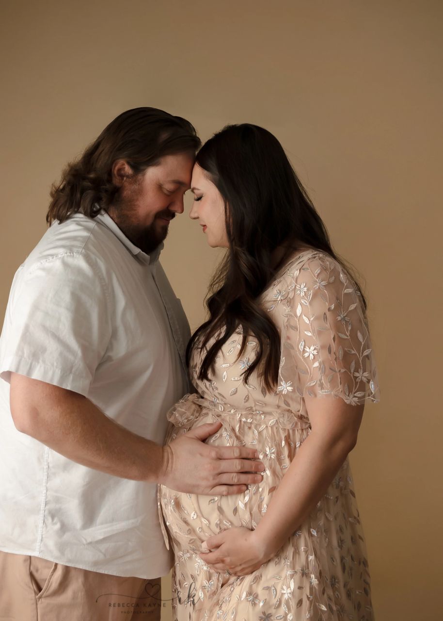 mom and dad snuggling in maternity portrait session