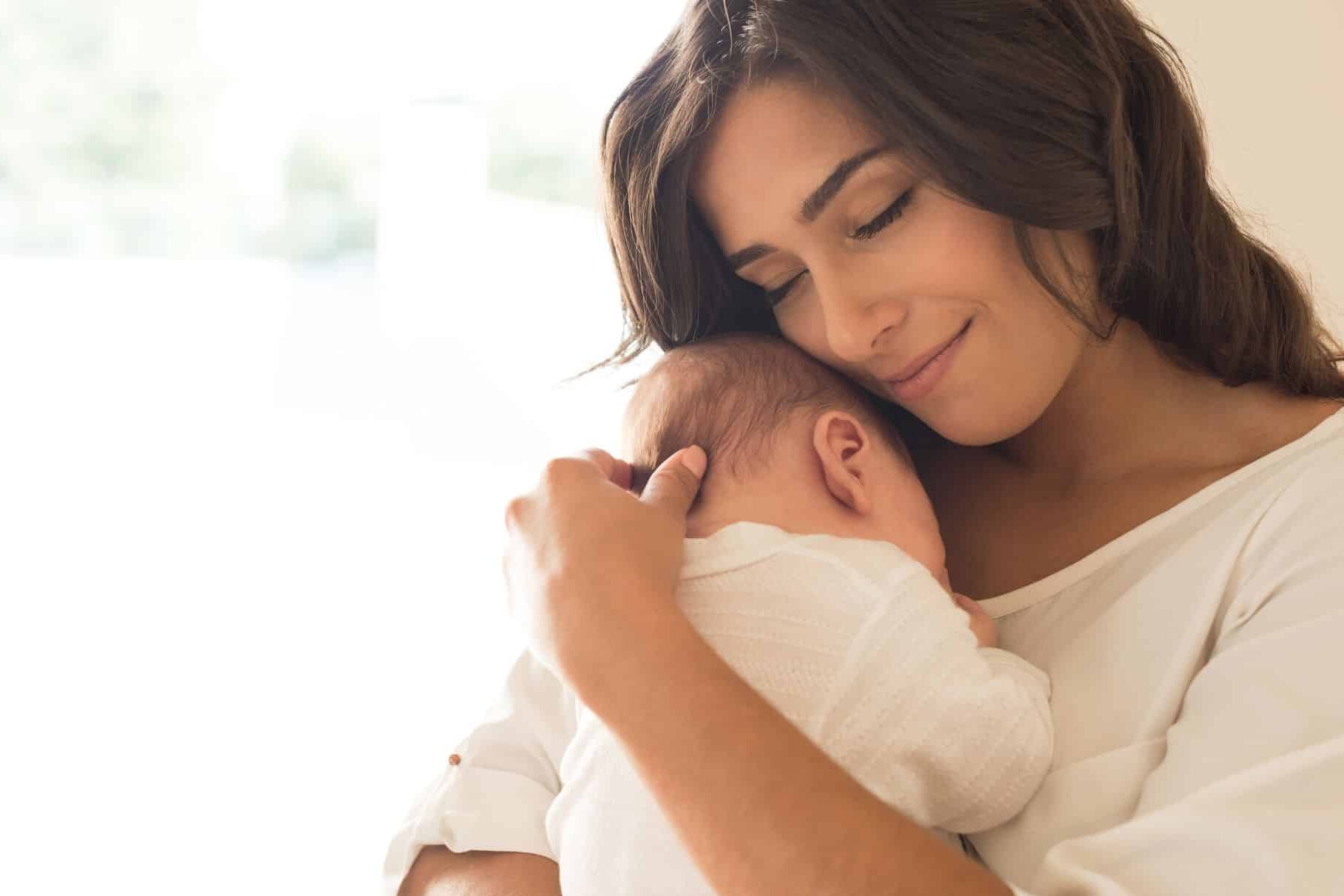 mom snuggles her newborn baby