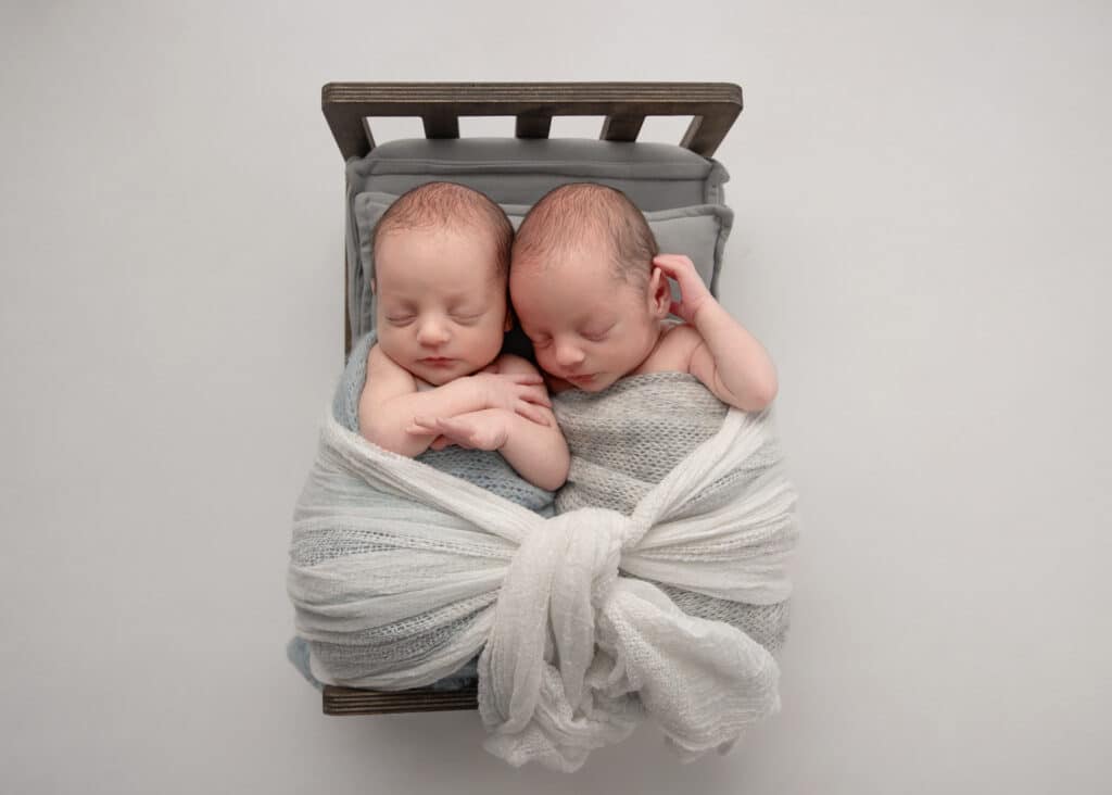 two twin boys on a bed in a utah twin newborn photography session